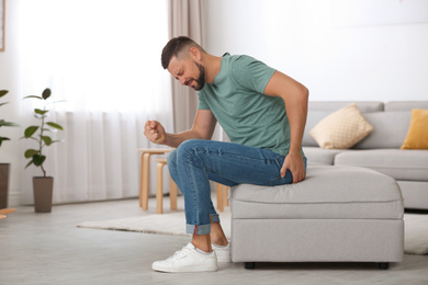 Photo of Man suffering from hemorrhoid in living room