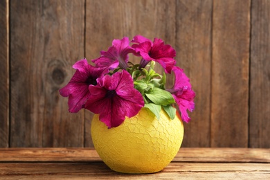 Beautiful pink petunia flowers in plant pot on wooden table