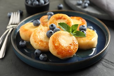 Delicious cottage cheese pancakes with blueberries on black table, closeup