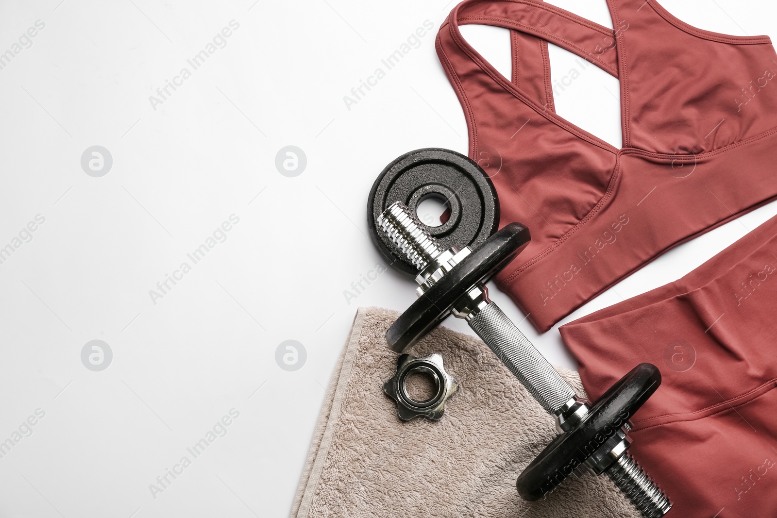 Photo of Sportswear, towel and dumbbell on white background, flat lay with space for text