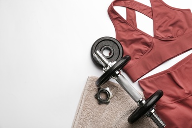 Photo of Sportswear, towel and dumbbell on white background, flat lay with space for text