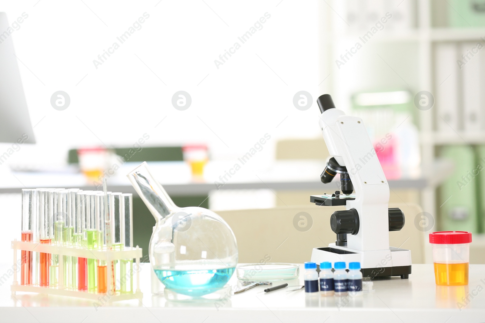 Photo of Laboratory glassware and microscope on table indoors. Research and analysis