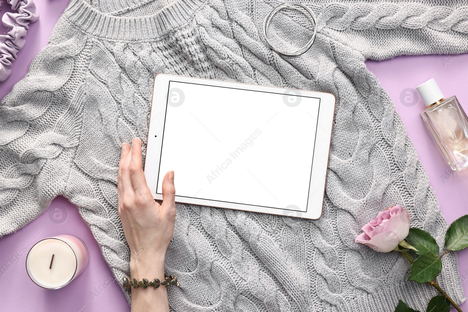 Photo of Woman with modern tablet and sweater on violet background, top view. Space for text