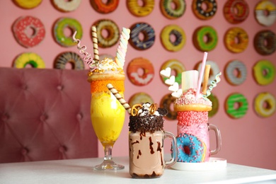 Tasty milk shakes with sweets in glassware on table at cafe
