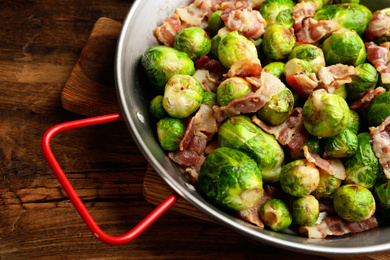 Delicious Brussels sprouts with bacon on wooden table, closeup