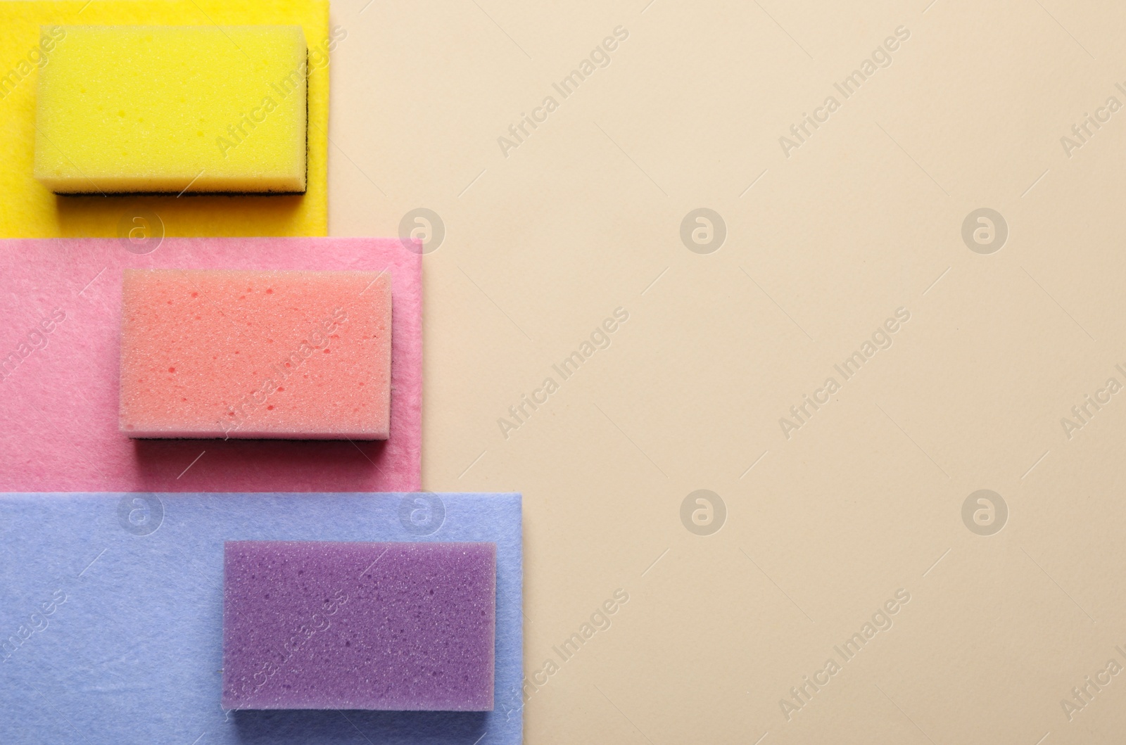 Photo of New sponges and rags on beige background, top view. Space for text