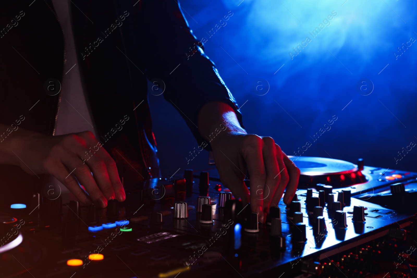 Photo of DJ creating music on modern console mixer in night club, closeup