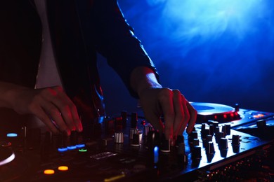 Photo of DJ creating music on modern console mixer in night club, closeup