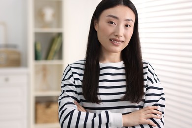 Portrait of smiling businesswoman with crossed arms in office