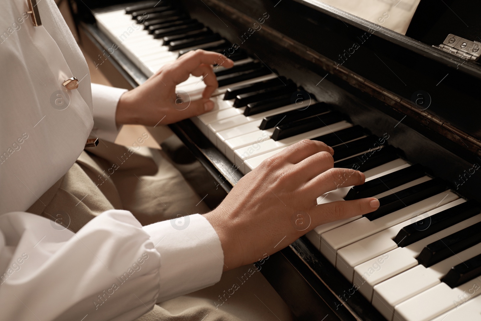 Photo of Young woman playing piano, closeup. Music lesson