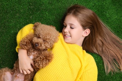 Photo of Little child with cute puppy on green grass, top view. Lovely pet