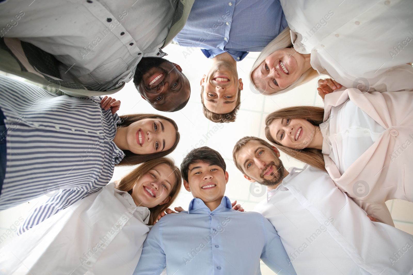 Photo of People standing together against light background, bottom view. Unity concept