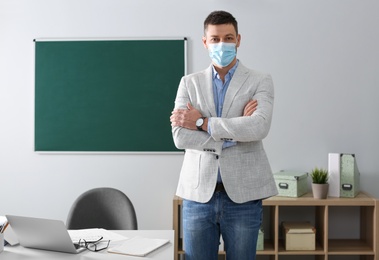 Photo of Teacher with protective mask in classroom. Reopening after Covid-19 quarantine