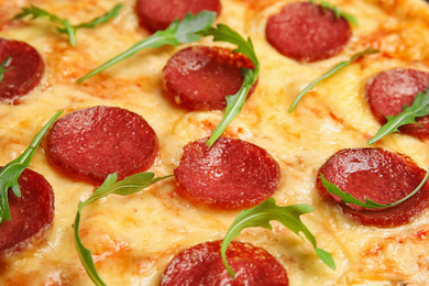 Photo of Tasty pepperoni pizza with arugula as background, closeup