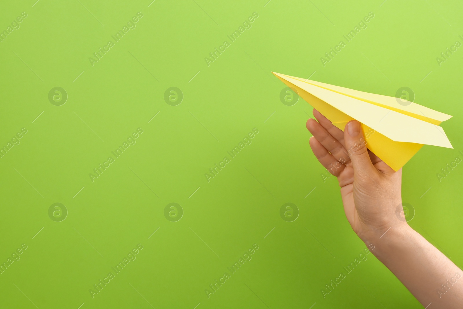 Photo of Woman holding paper plane on green background, closeup. Space for text