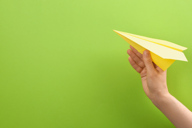 Photo of Woman holding paper plane on green background, closeup. Space for text