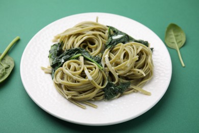 Photo of Tasty pasta with spinach and sauce on green table