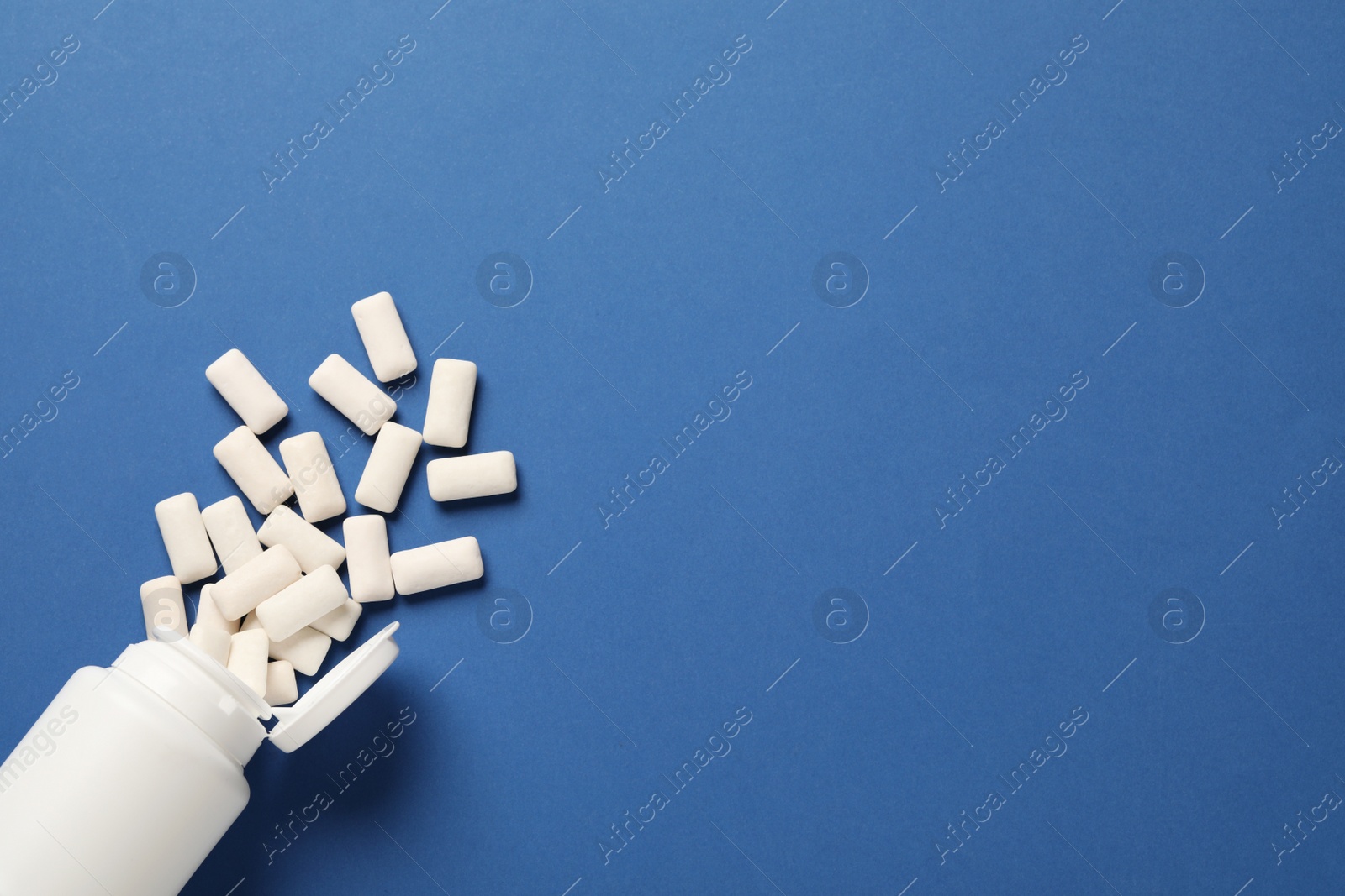 Photo of Jar and chewing gum pieces on blue background, flat lay. Space for text