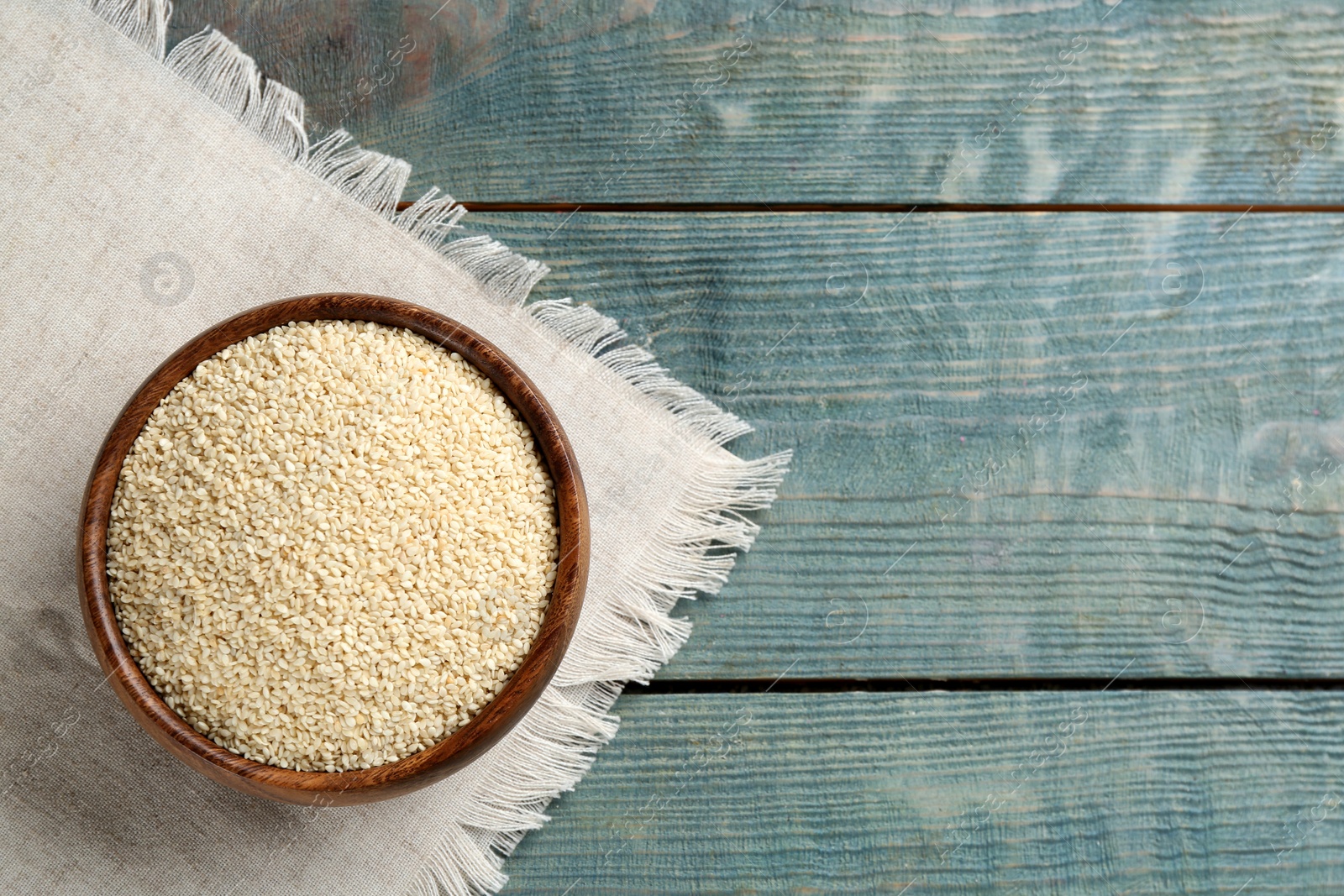 Photo of White sesame seeds on light blue wooden table, flat lay. Space for text