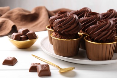 Delicious cupcake and chocolate pieces on white wooden table, closeup