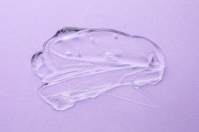 Clear cosmetic gel on violet background, top view