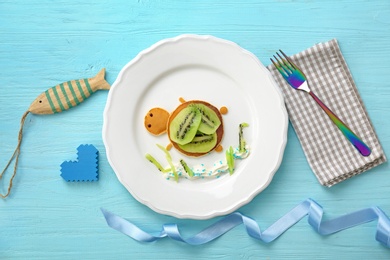 Flat lay composition with pancakes in form of turtle on wooden background. Creative breakfast ideas for kids