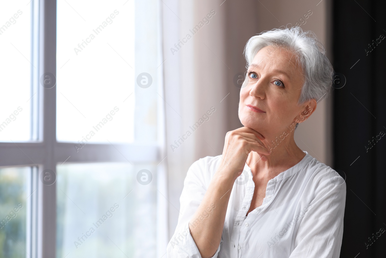 Photo of Happy mature woman near window indoors, space for text. Smart aging