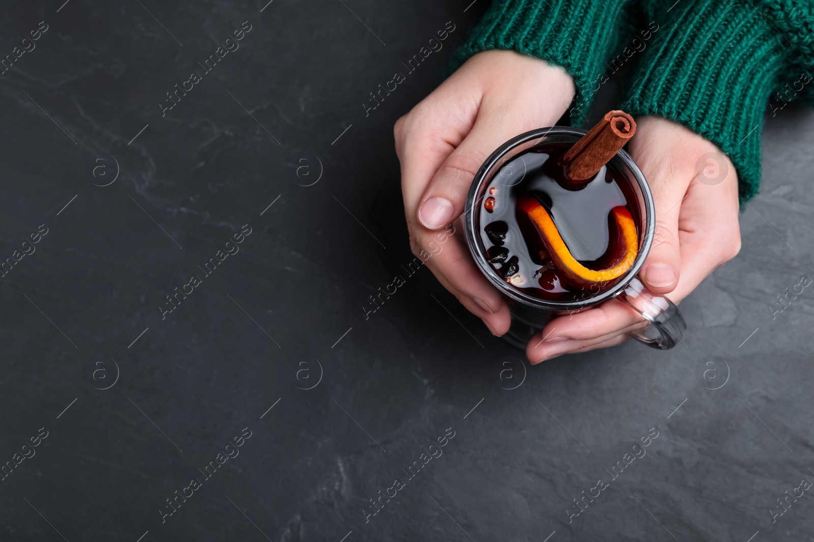 Photo of Woman with cup of mulled wine at black table, top view. Space for text