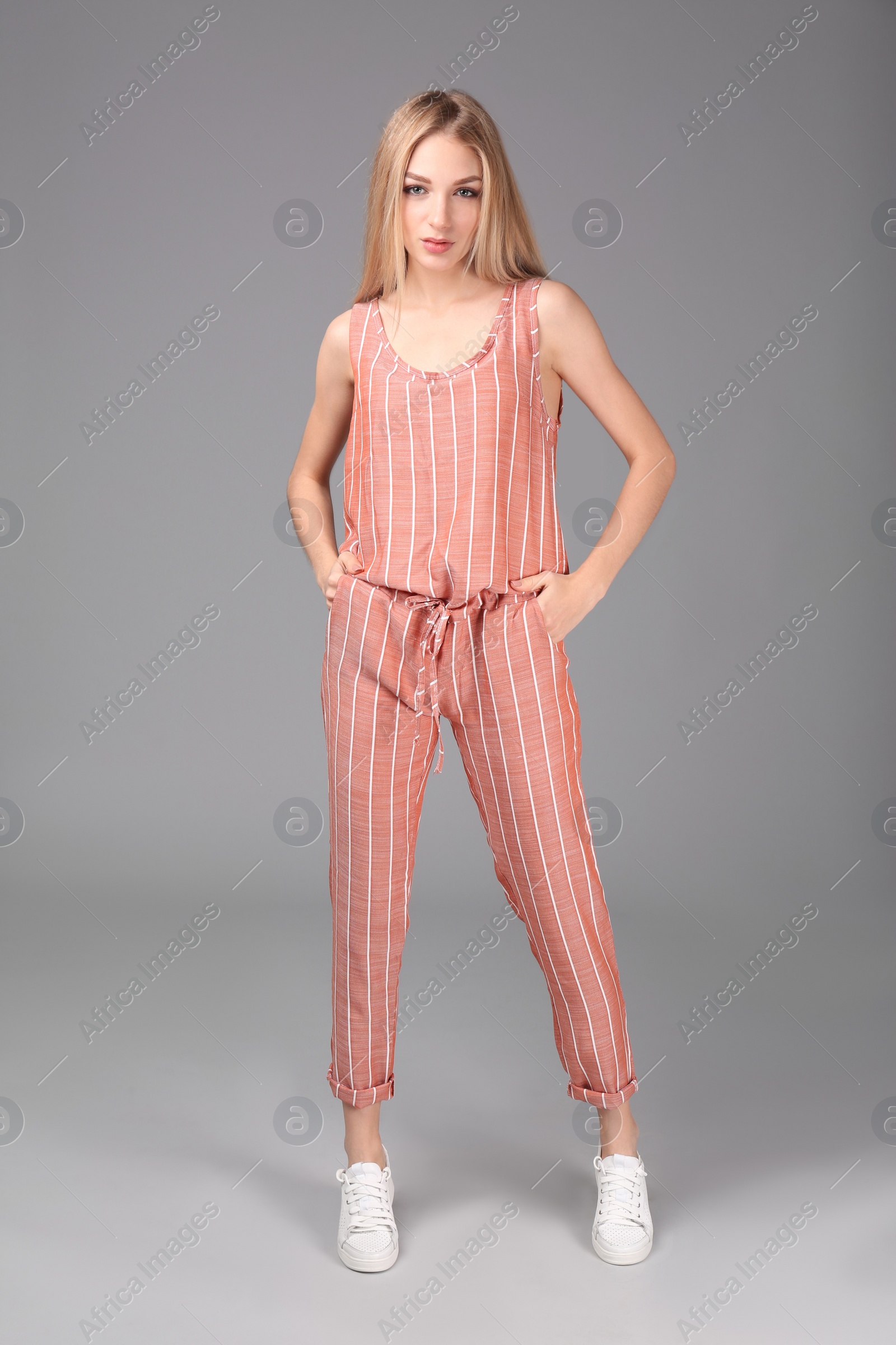 Photo of Young stylish woman in trendy sport shoes on grey background