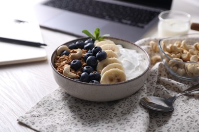 Delicious granola in bowl on white wooden table, closeup