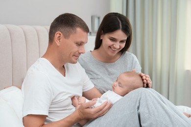 Happy family with their cute sleeping baby on bed at home