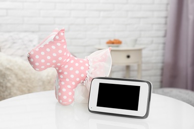 Photo of Modern baby monitor and toy dog on table indoors, space for text. CCTV equipment