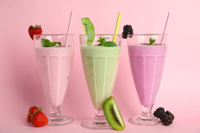 Photo of Tasty fresh milk shakes and ingredients on pink background