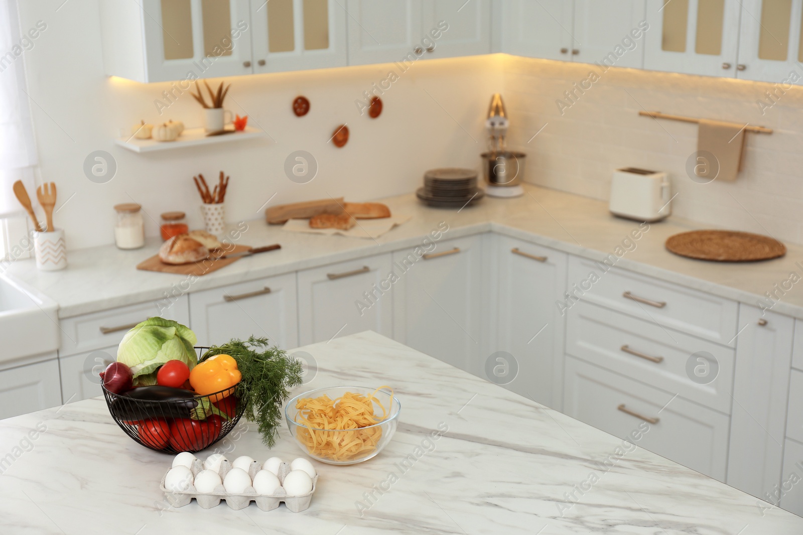 Photo of Modern kitchen interior with different products on white marble table