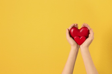 Woman holding decorative hearts in hands on color background, space for text