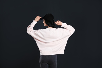 Photo of Young woman in sweater on black background. Mock up for design