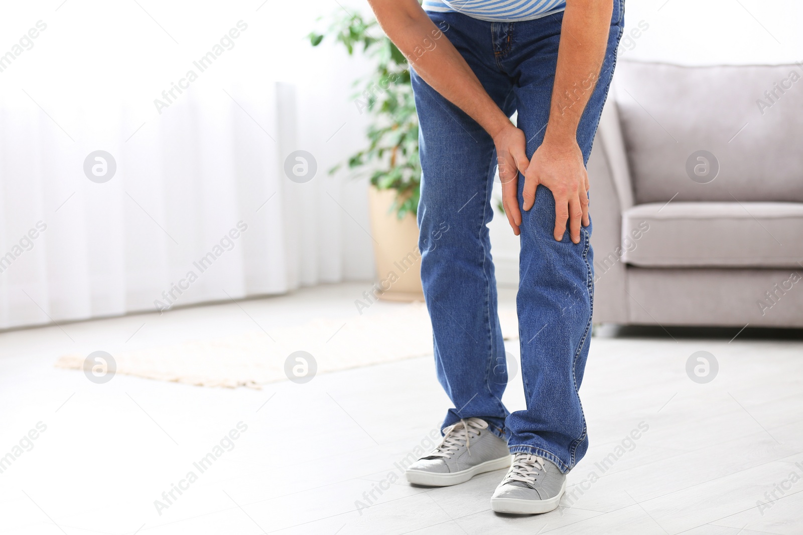 Photo of Senior man suffering from knee pain at home, closeup. Space for text