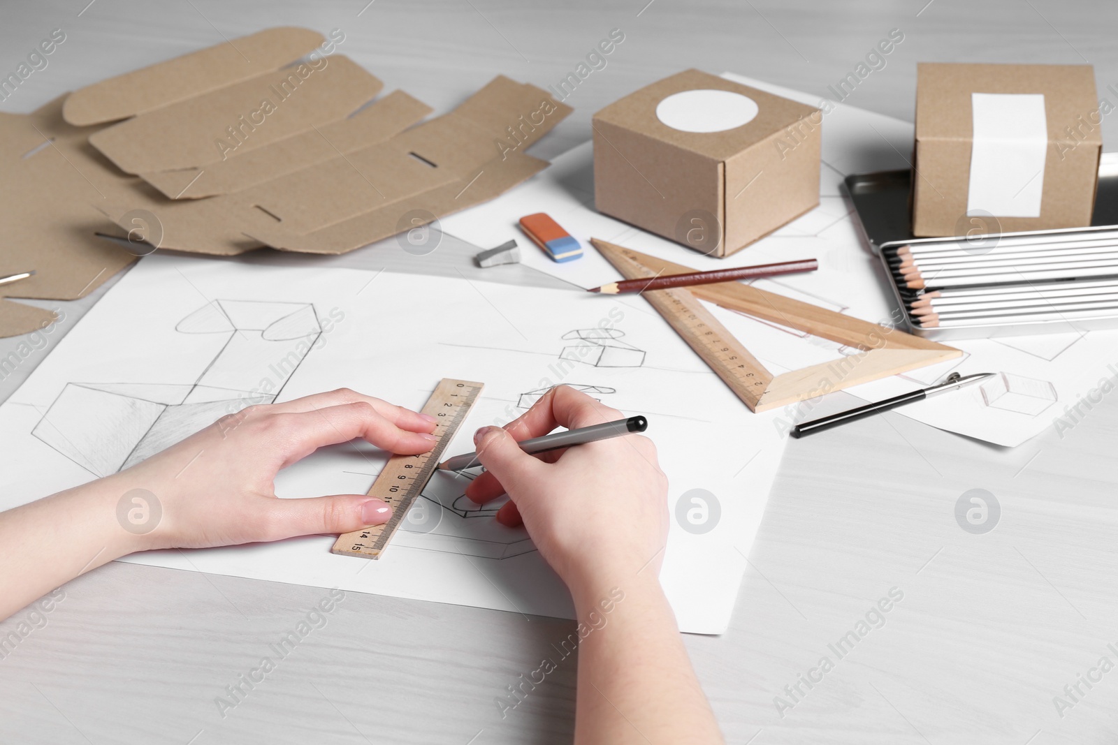 Photo of Woman creating packaging design at light wooden table, closeup