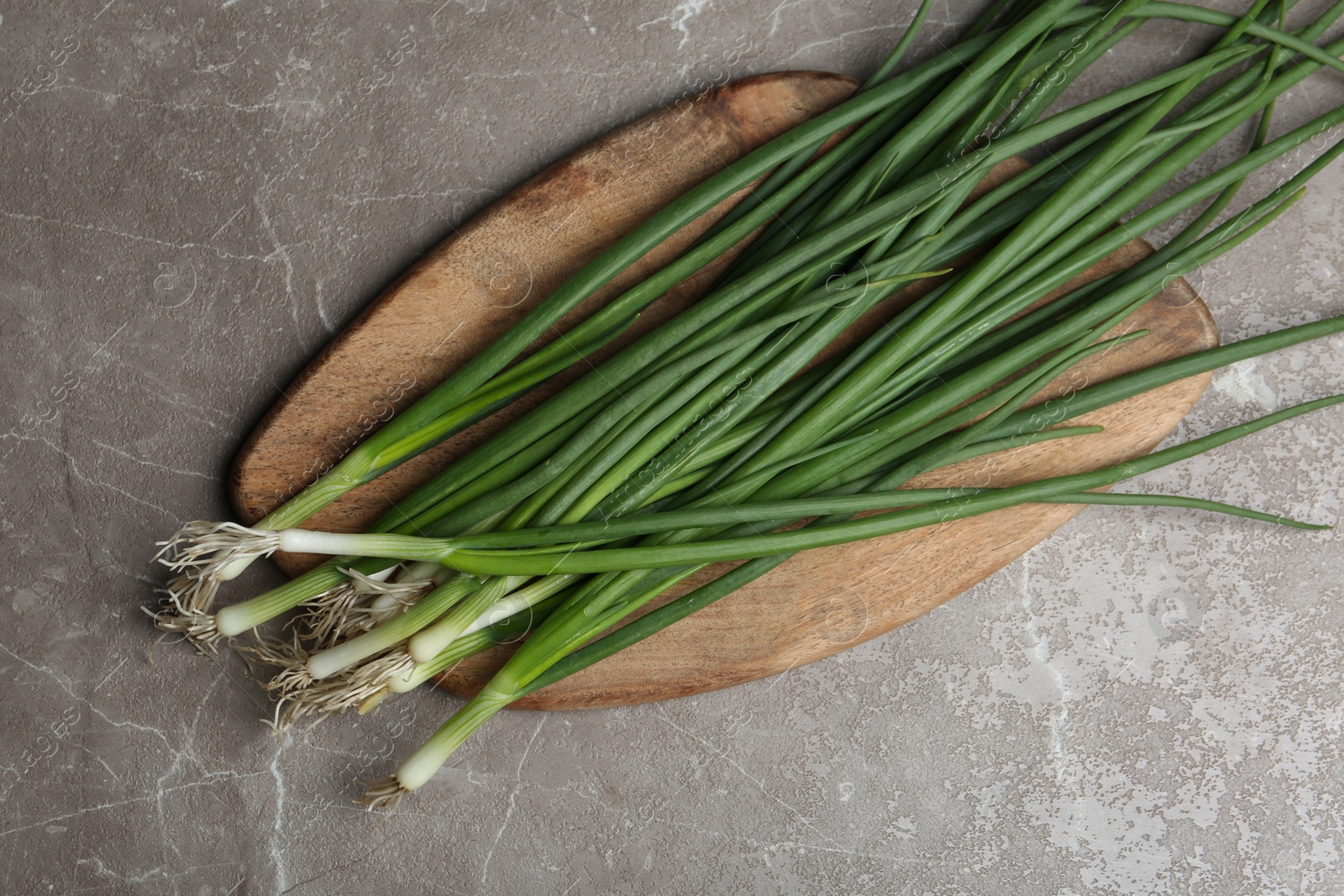 Photo of Fresh green spring onions on grey marble table, top view