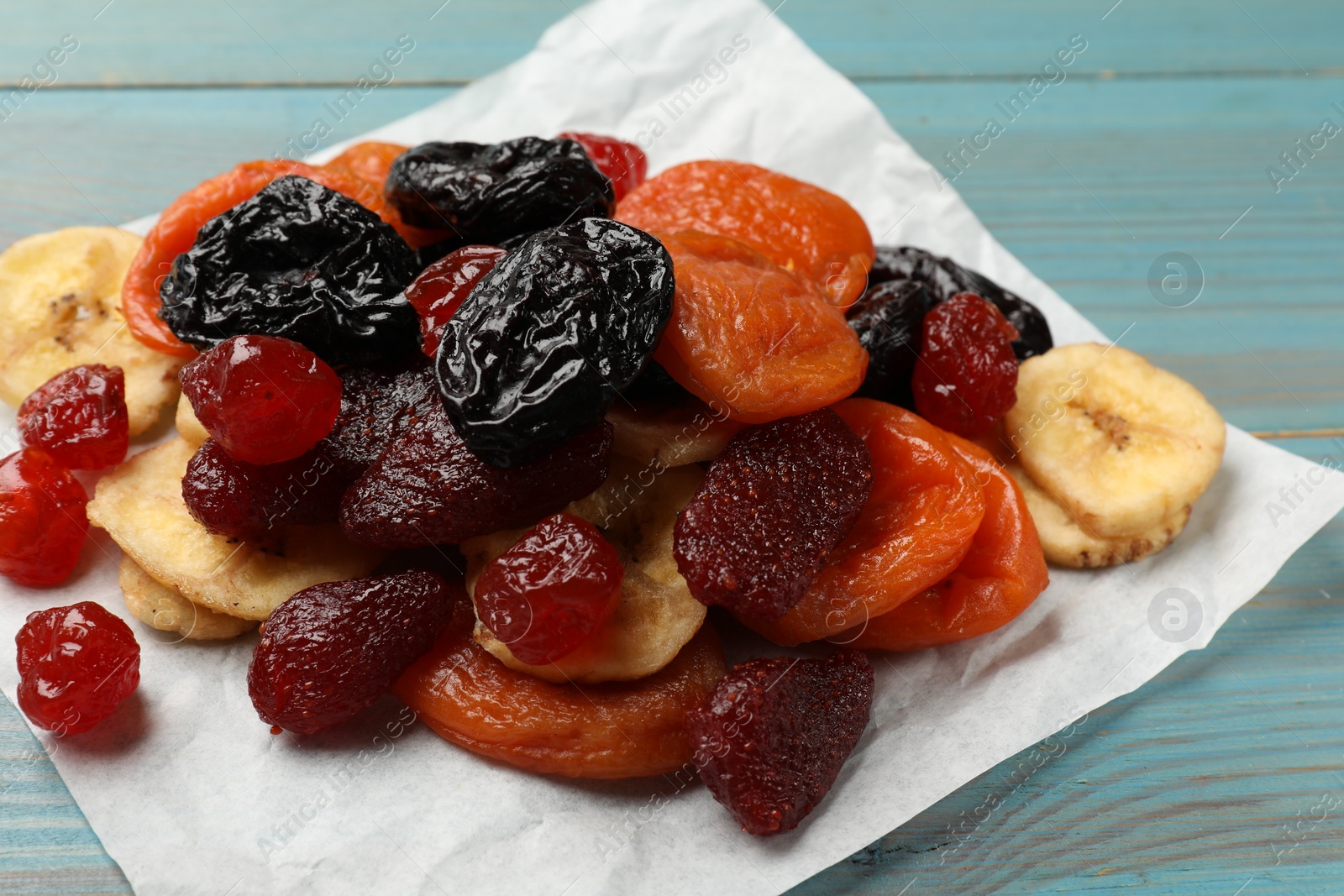 Photo of Mix of delicious dried fruits on light blue wooden table, closeup