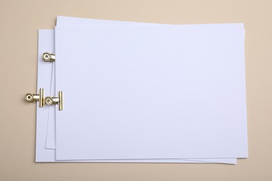 Photo of Sheets of paper with clips on beige background, top view
