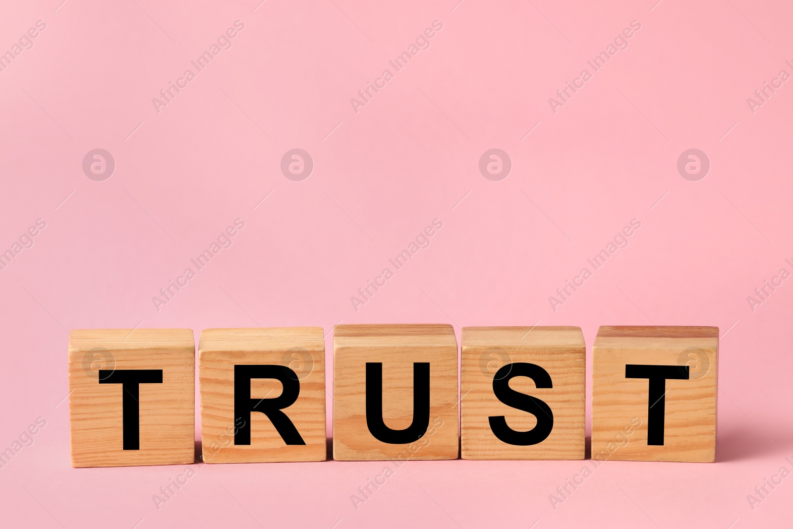 Photo of Cubes with word TRUST on pink background. Space for text