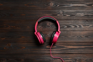 Stylish headphones on wooden background, top view