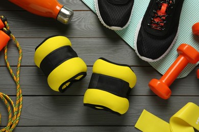Photo of Yellow weighting agents and sport equipment on grey wooden table, flat lay