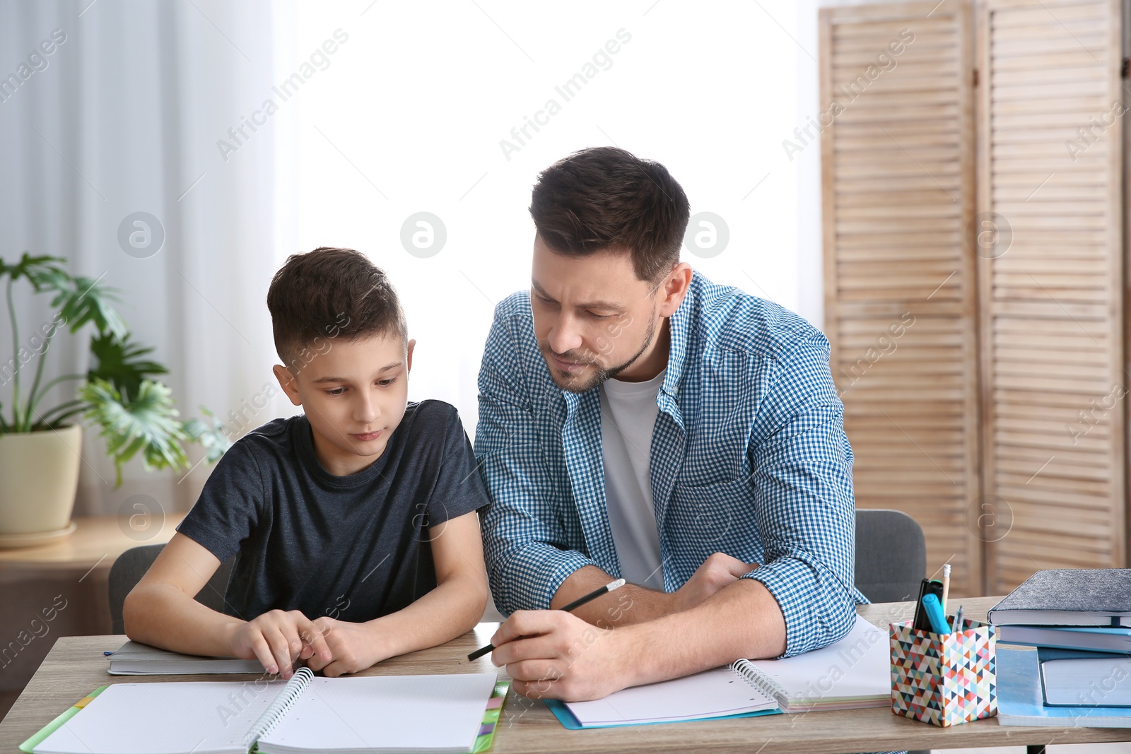 Photo of Dad helping his son with homework in room