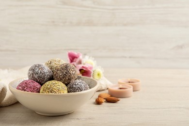 Different delicious vegan candy balls on white wooden table. Space for text