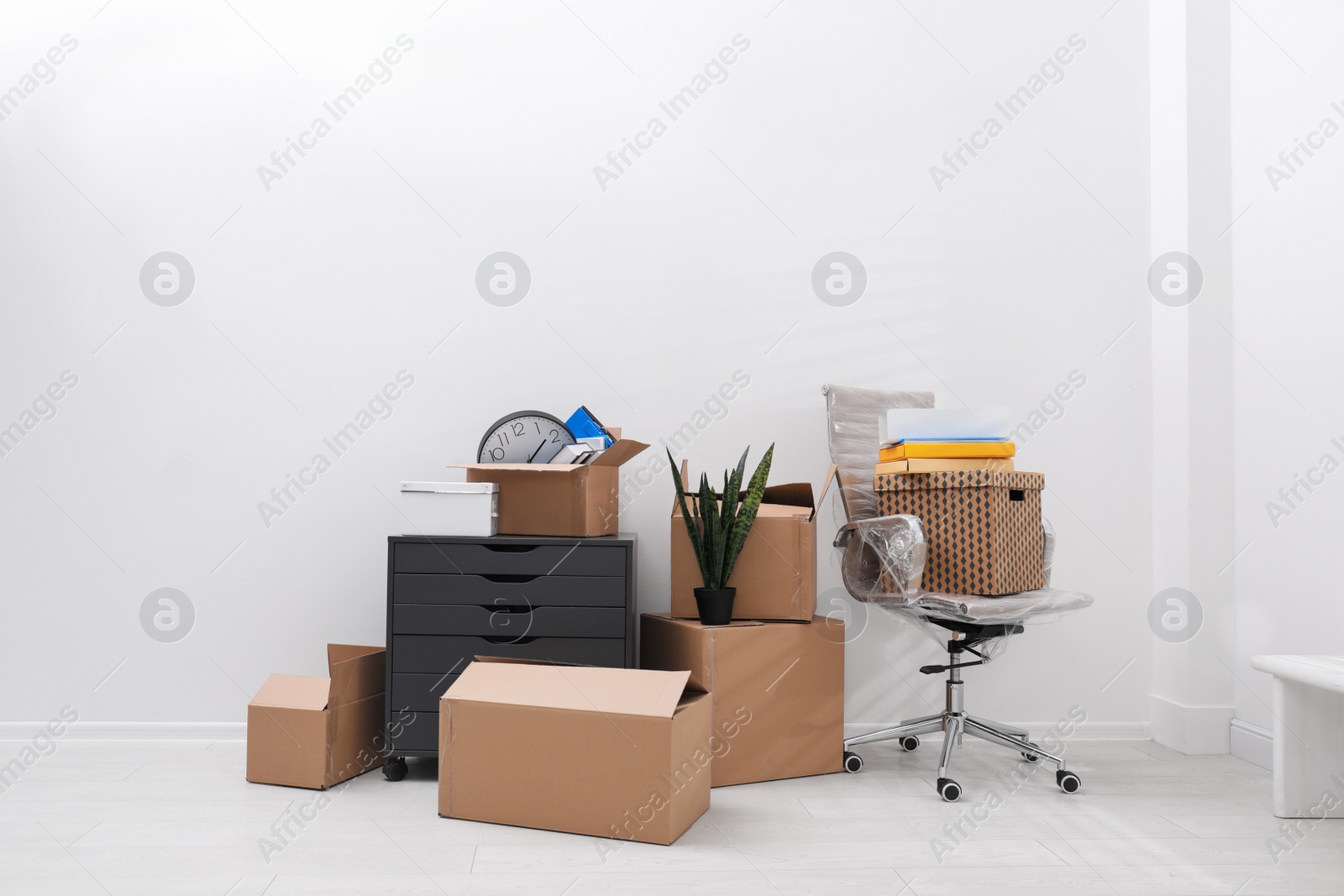 Photo of Cardboard boxes and packed belongings near white wall. Moving day