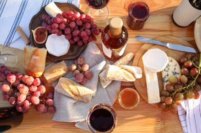 Red wine and snacks served for picnic on wooden table, flat lay