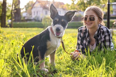 Teenage girl with her cute dog resting on green grass in park