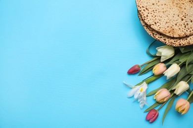 Photo of Tasty matzos and fresh tulips on light blue background, flat lay with space for text. Passover (Pesach) celebration